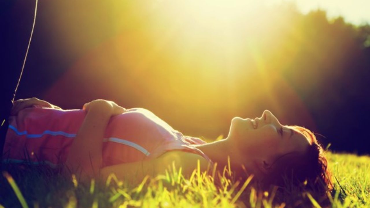 Mulher deitada na grama em dia ensolarado